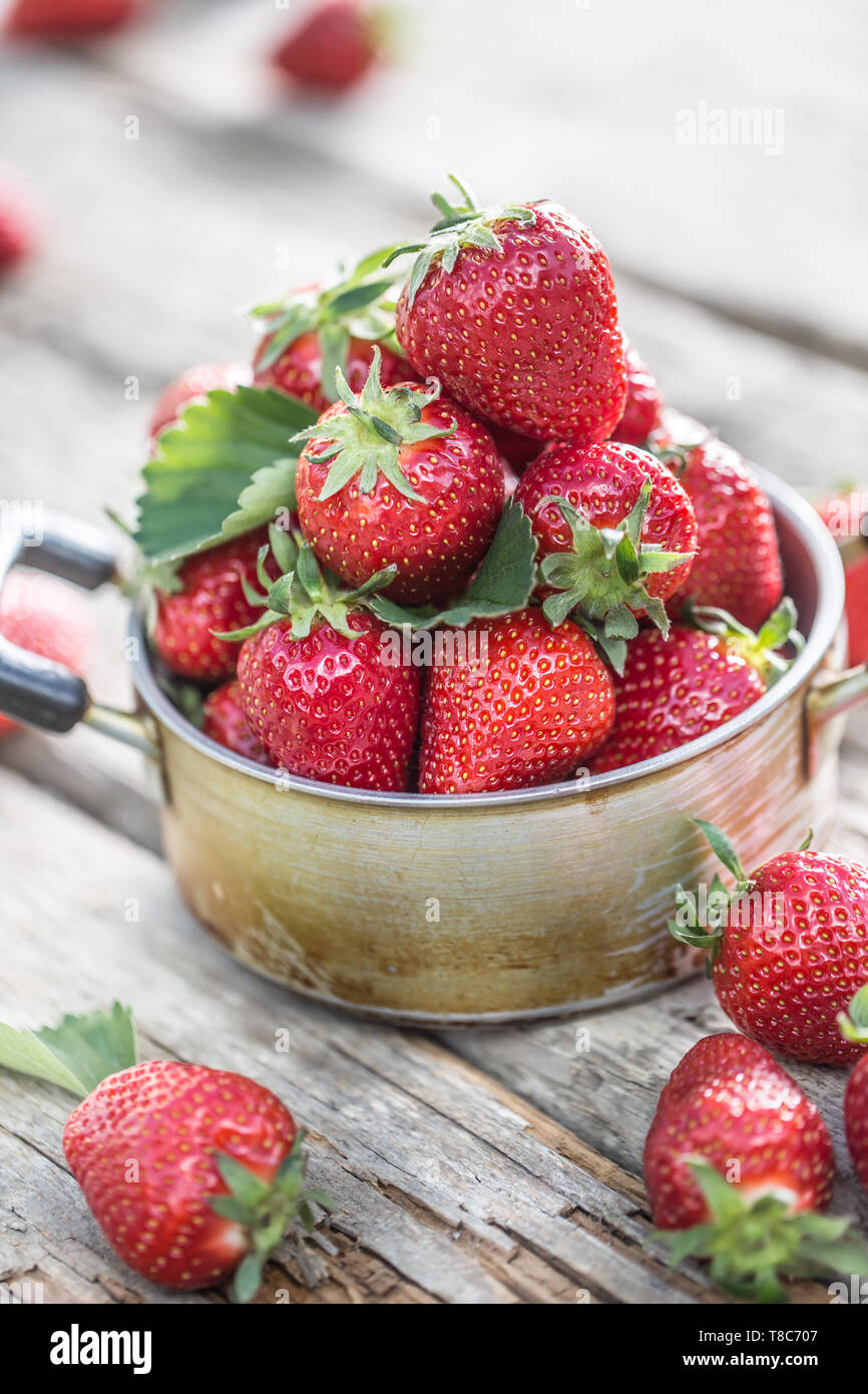Fresh ripe strawberries in vintage kitchen pot on old garden table Stock Photo