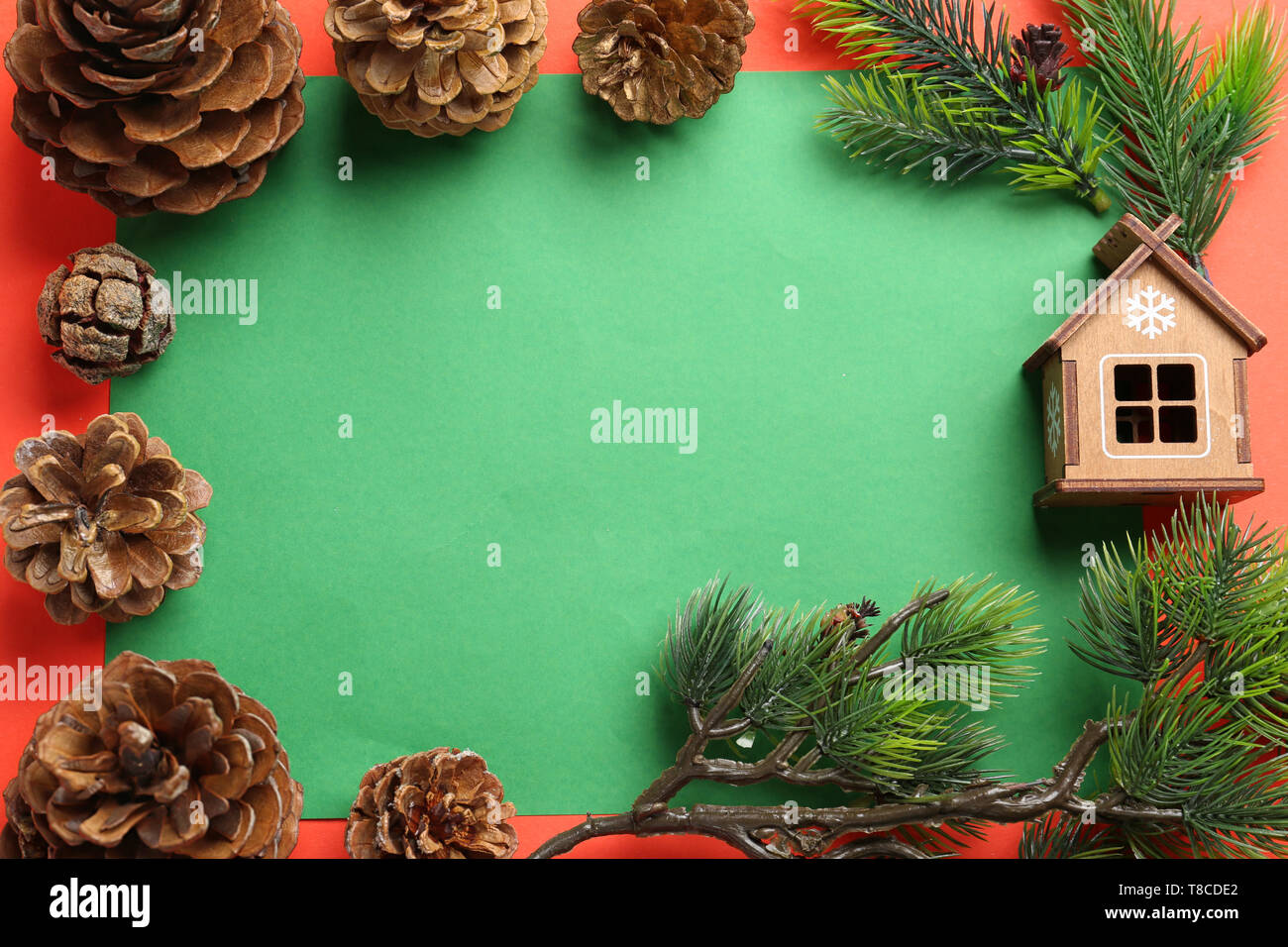 Frame made of cones and Christmas tree branches on color background