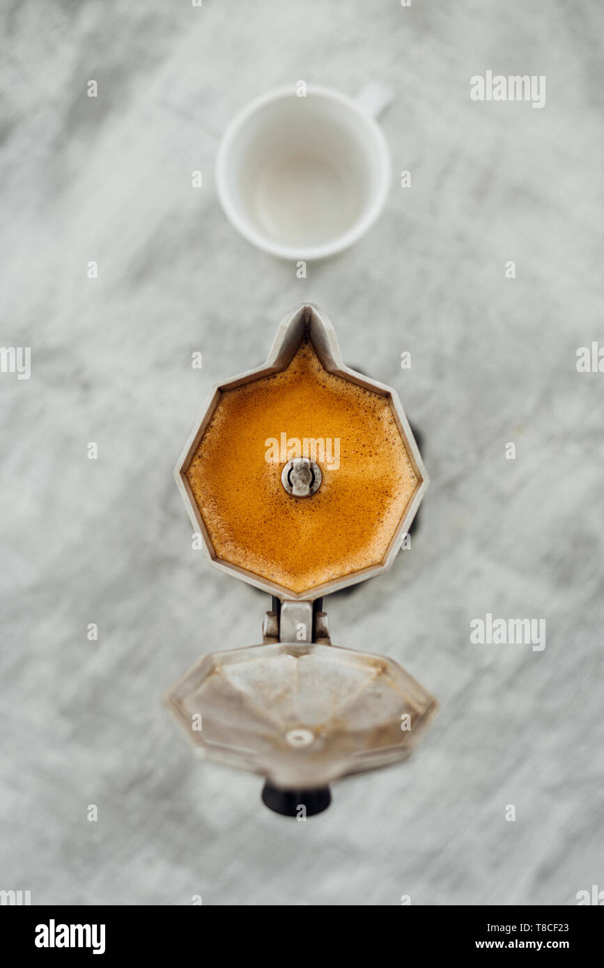 Moka pot with fresh brewed coffee and white cup on grey background Stock Photo