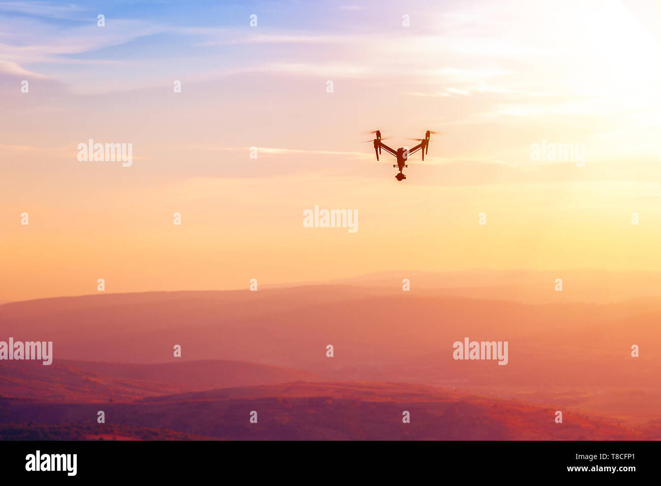 Drone flying over the hills in the sunset. The drone with the professional camera takes pictures Stock Photo