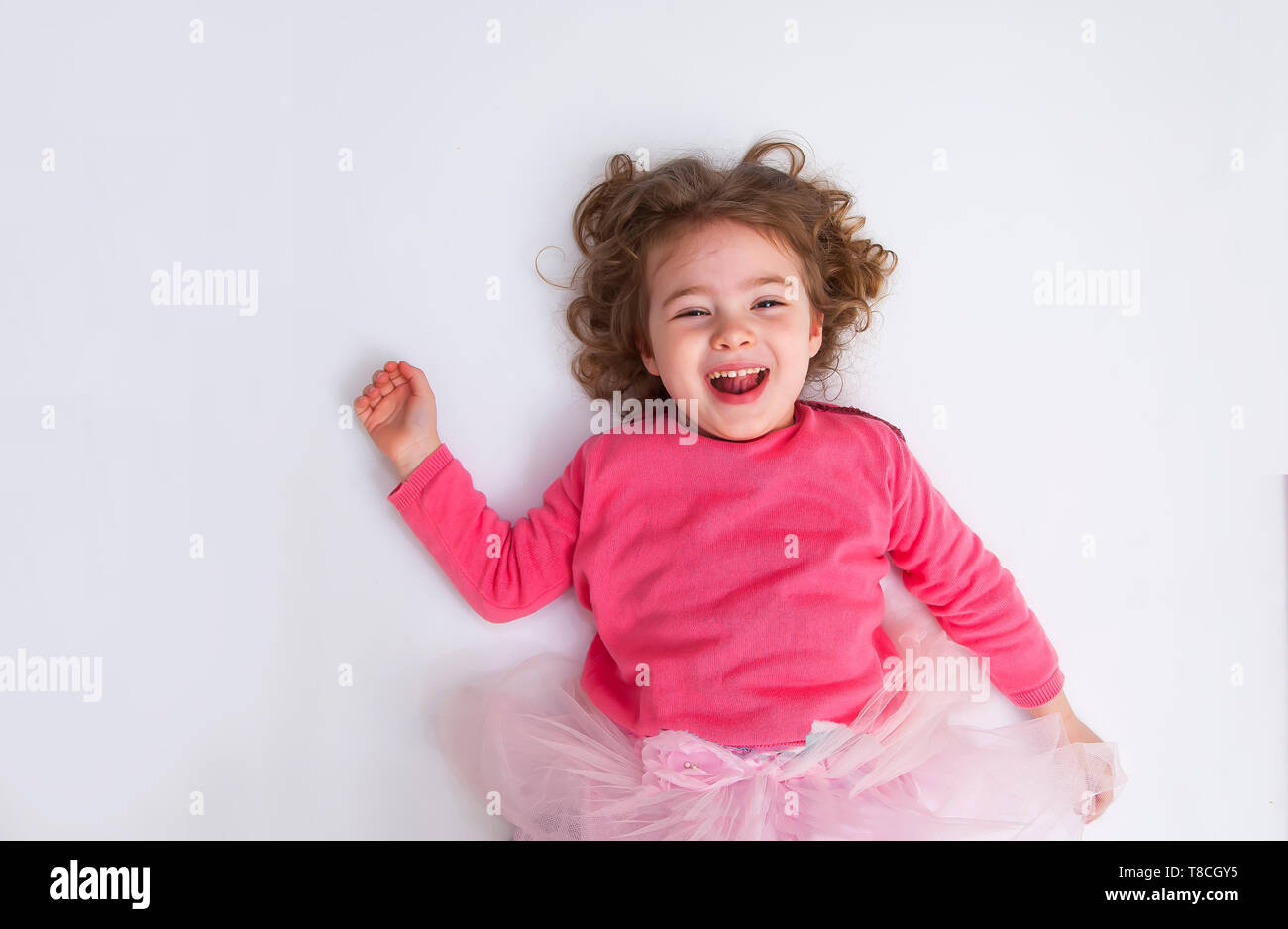 little girl lies on the white floor and smile Stock Photo - Alamy