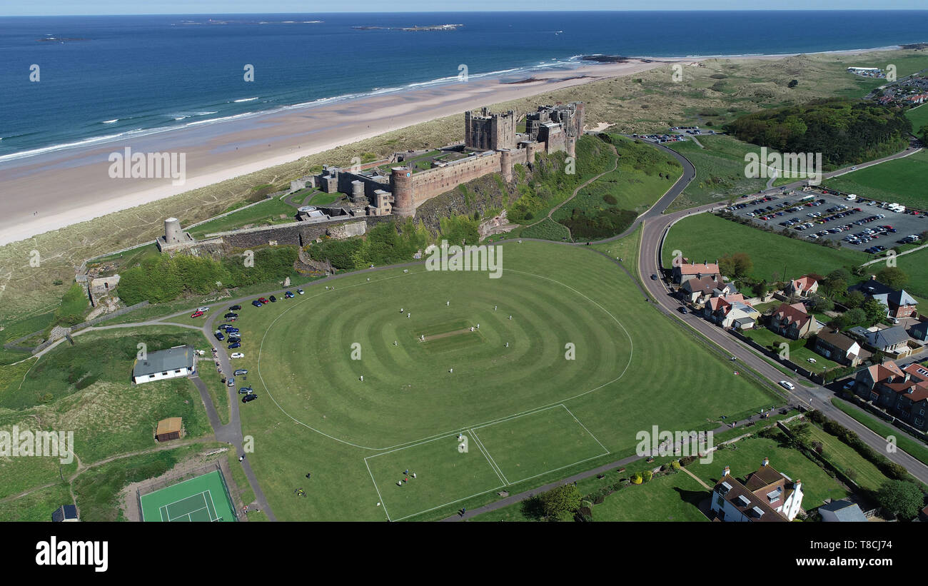 Bamburgh Cricket team play their first match of the season against Ellingham in the shadow of Bamburgh Castle in Northumberland. Stock Photo