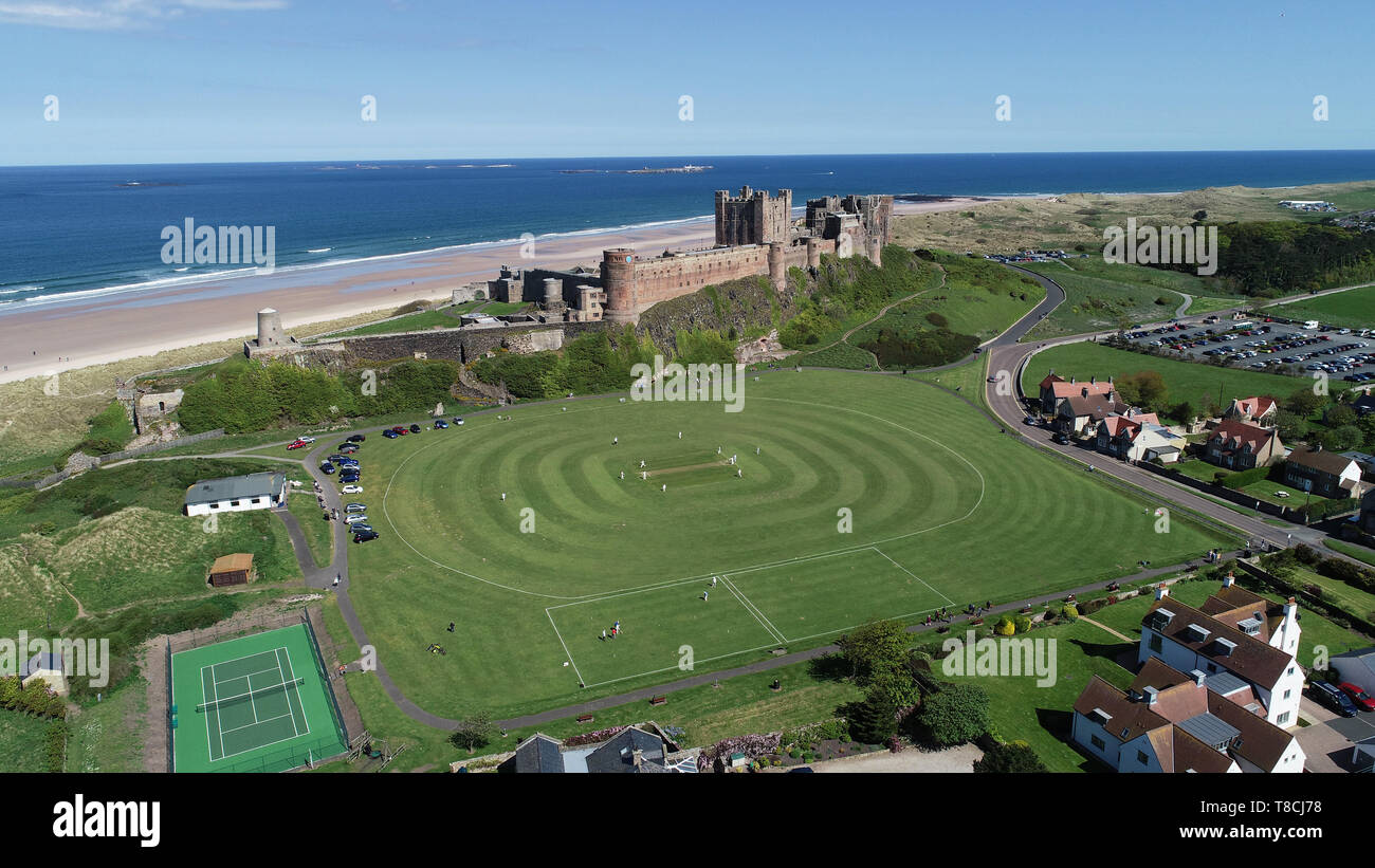 Bamburgh Cricket team play their first match of the season against Ellingham in the shadow of Bamburgh Castle in Northumberland. Stock Photo