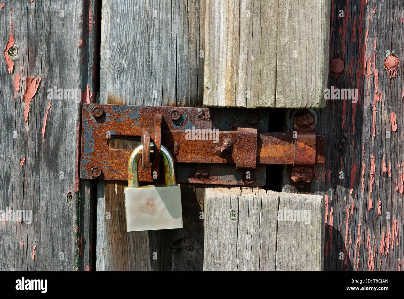 An old rusty padlock on wooden barn door Stock Photo