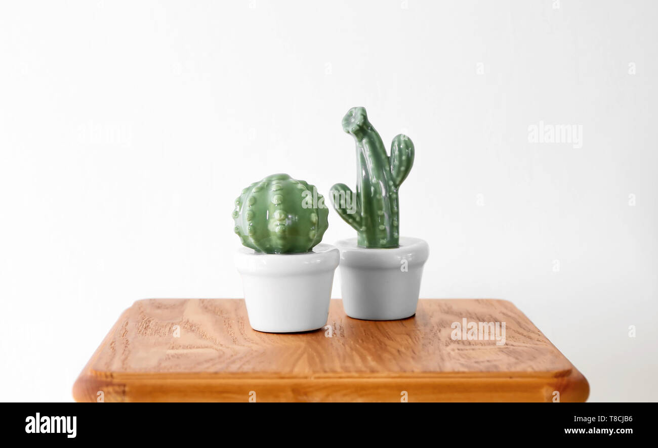 Ceramic cacti in pots on table against white background Stock Photo