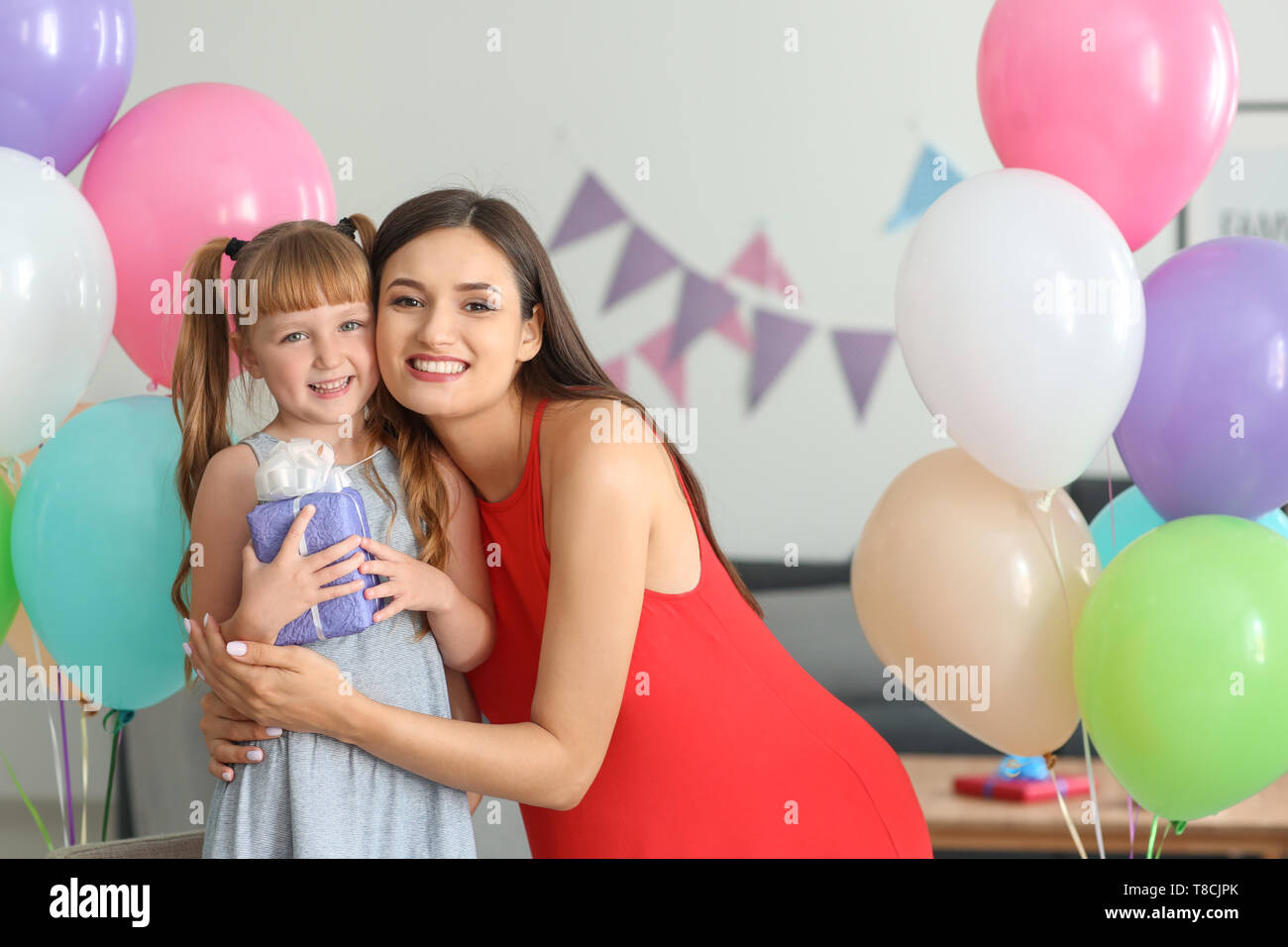 Cute little girl holding birthday gift from mother at home Stock Photo ...