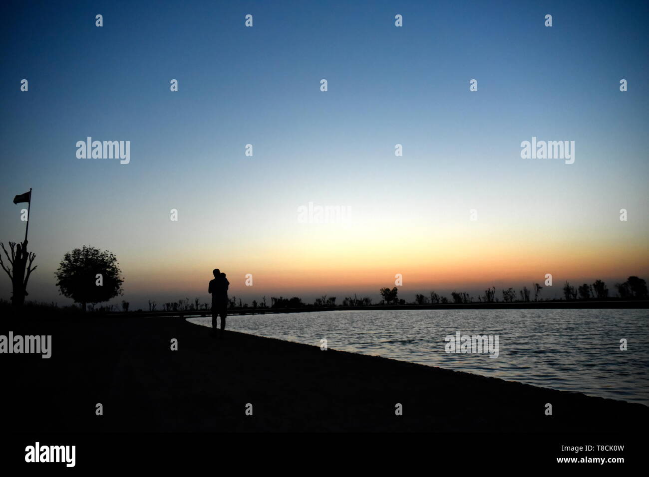 Silhouette Man and Baby at Lake on the sunset at Al Qudra love lake, Dubai, United Arab Emirates Stock Photo