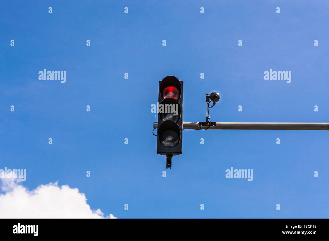 A traffic light and a surveillance camera on a pole mounted on the street. Stock Photo