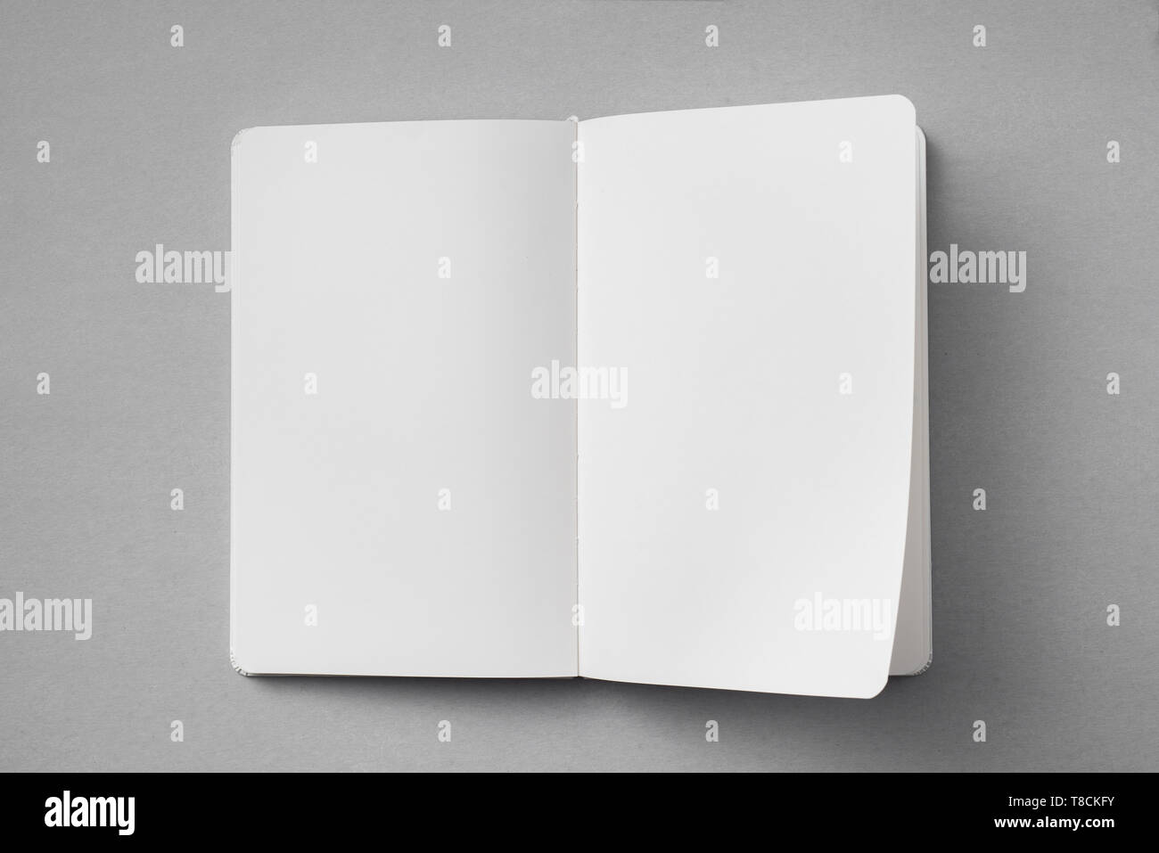 Notebook Flipped Open Design concept - top view of white notebook with blank open, turn and ...