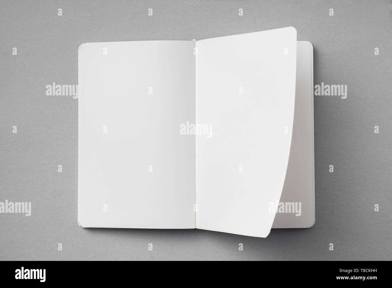 Notebook Flipped Open Design concept - top view of white notebook with blank open, turn and ...