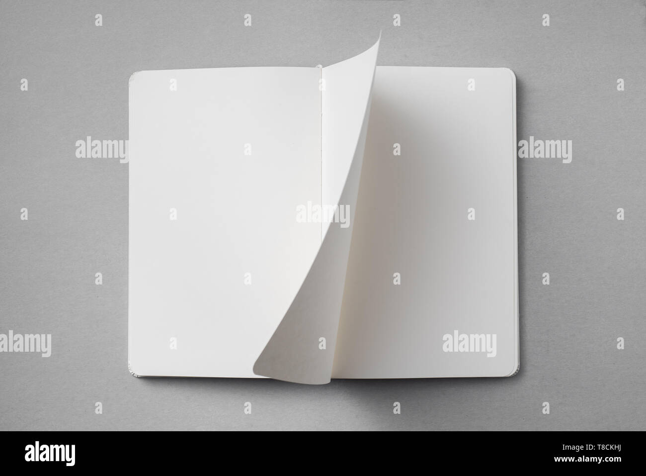 Notebook Flipped Open Design concept - top view of white notebook with blank open, turn and ...