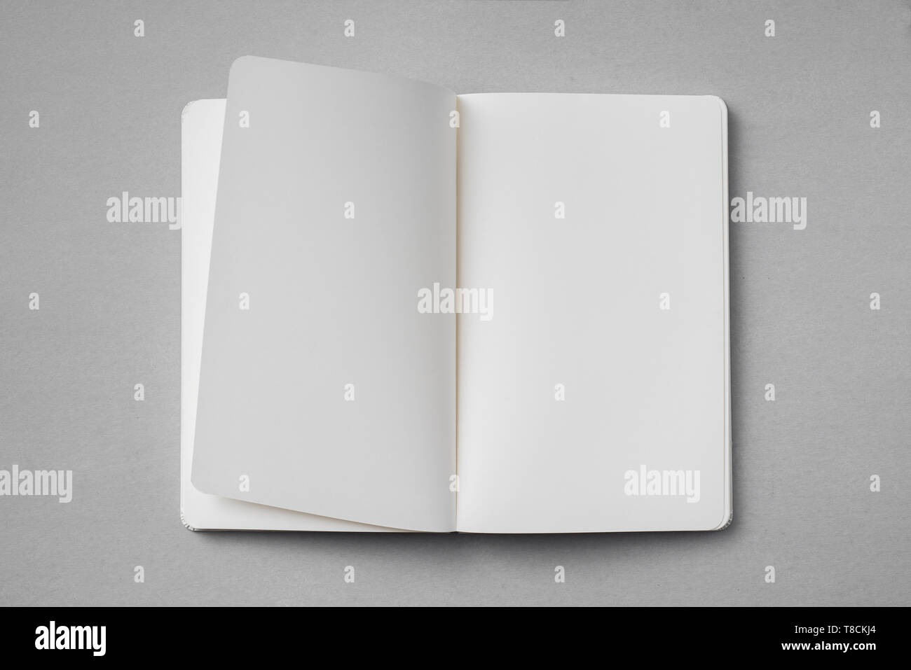 Notebook Flipped Open Design concept - top view of white notebook with blank open, turn and ...