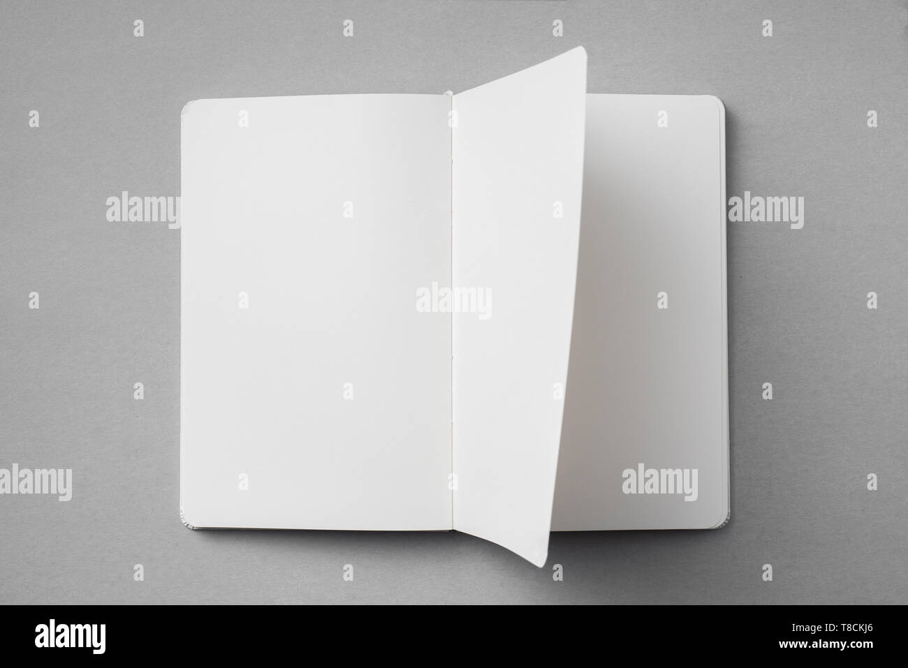 Notebook Flipped Open Design concept - top view of white notebook with blank open, turn and ...