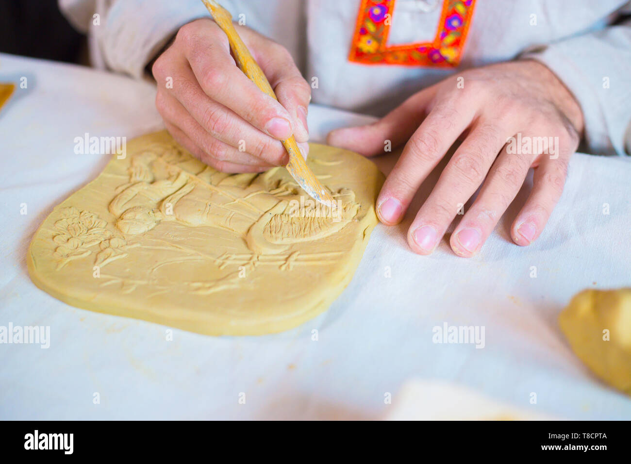 Professional male potter making clay stamp picture. Handwork, crafting and traditional arts concept Stock Photo