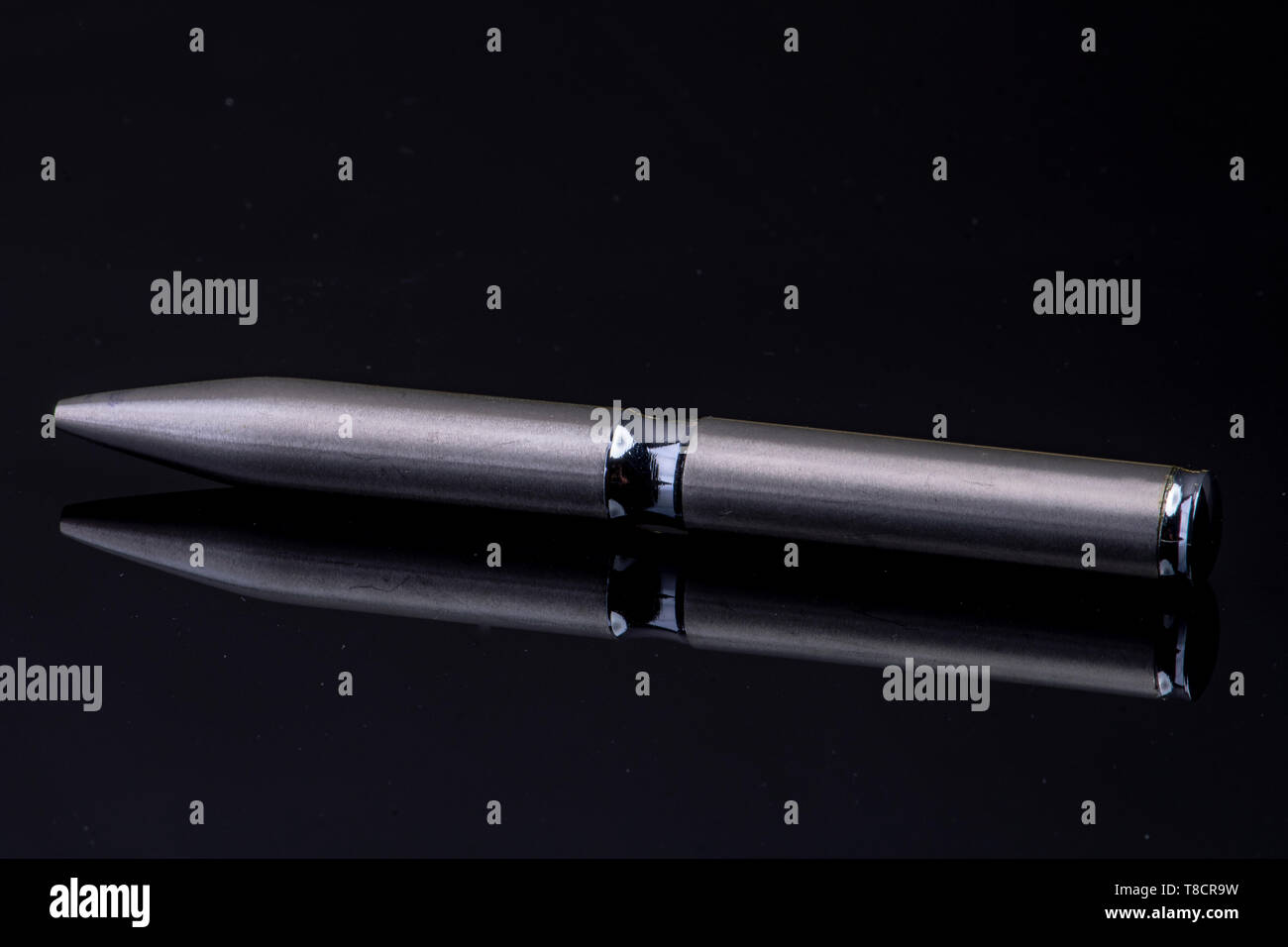 silver ballpoint pen on black reflective background Stock Photo