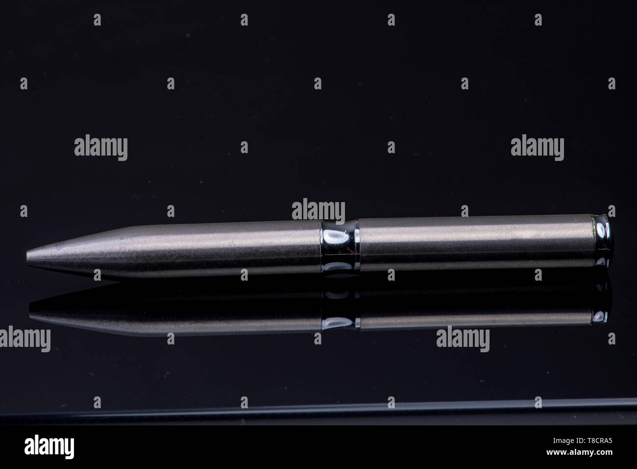silver ballpoint pen on black reflective background Stock Photo