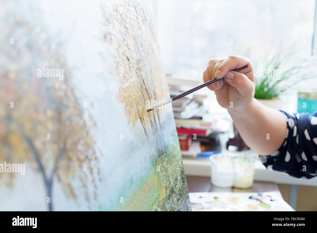 Female artist's hand in glove draws with an oil painting with a brush