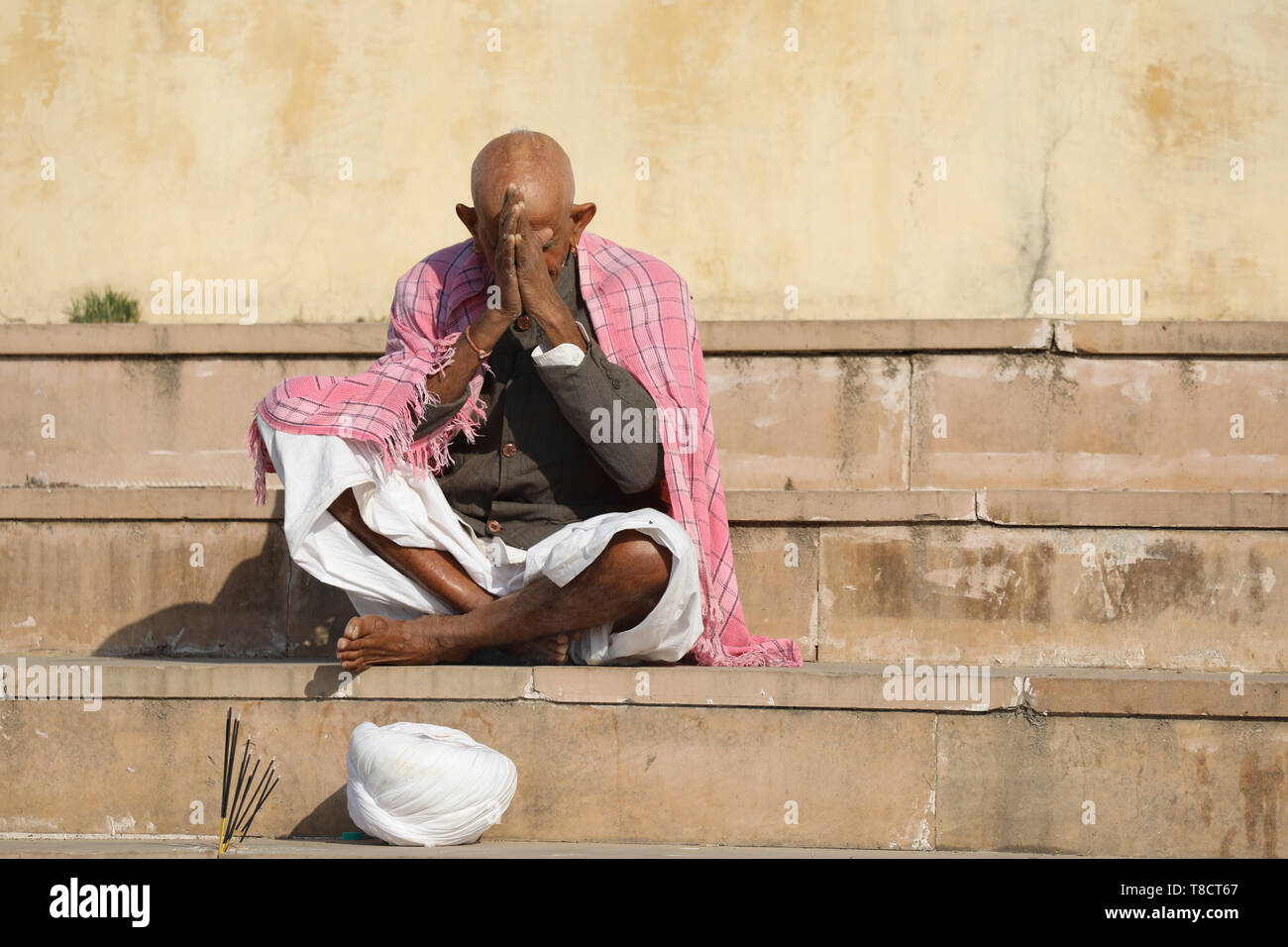 Old indian Man sitting on steps and praying Stock Photo
