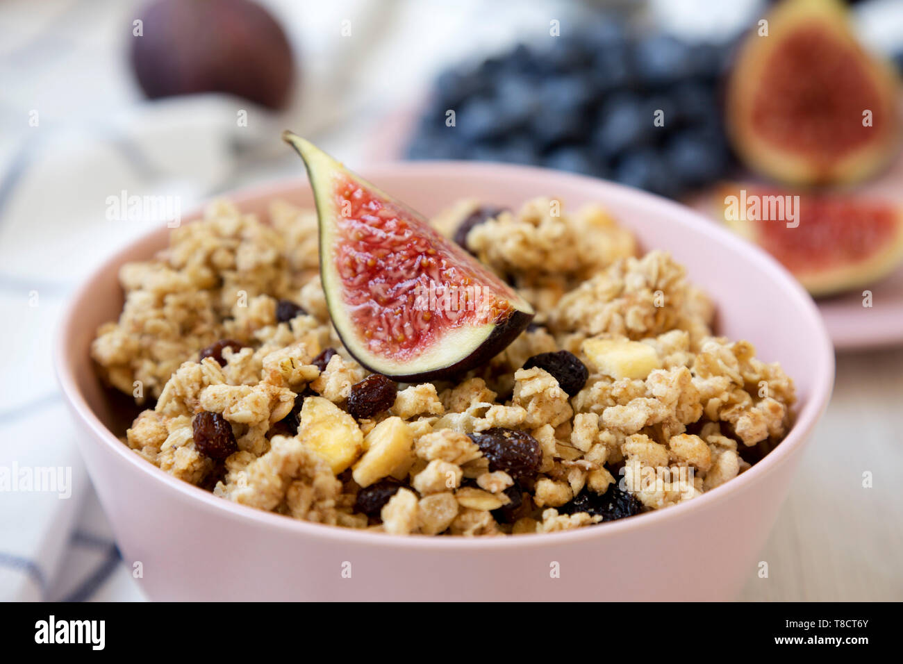 Pink bowl of fruit granola with fruits ready to eat, side view. Close