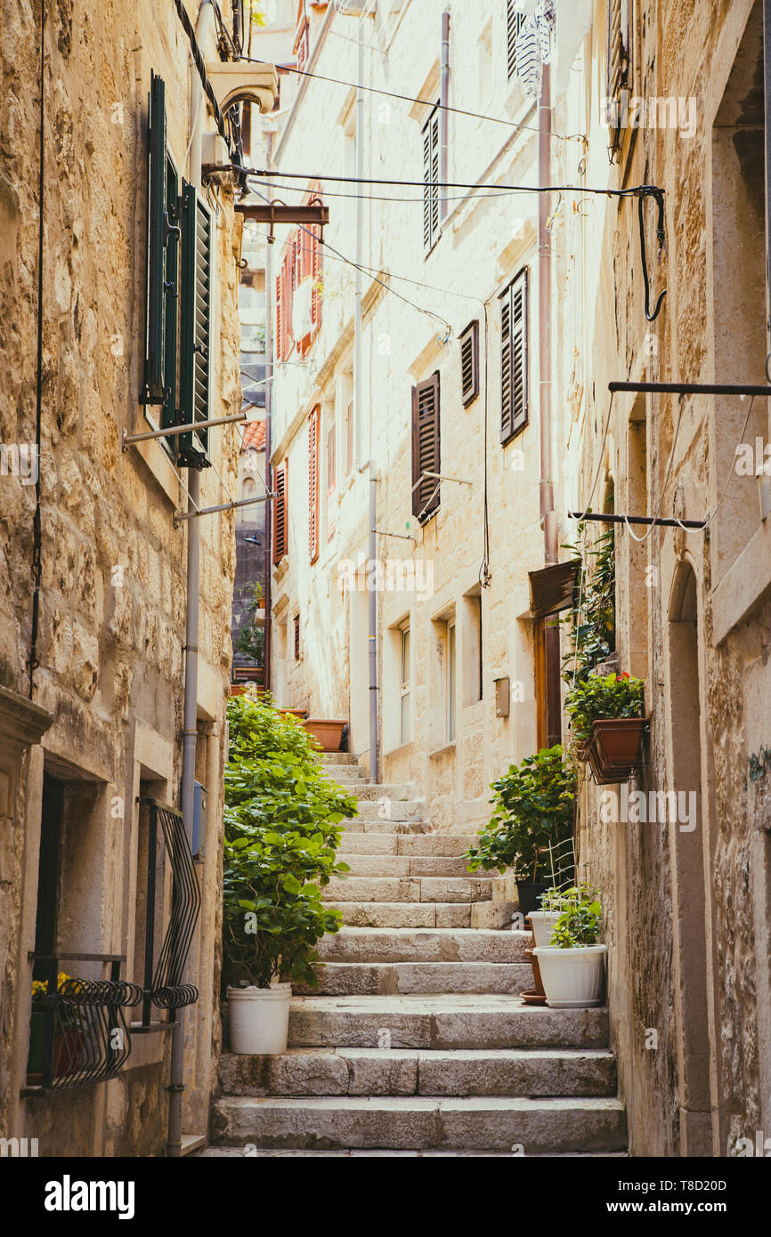 Scenic vertical view of small alleyway in an old town in Europe with golden light in summer Stock Photo