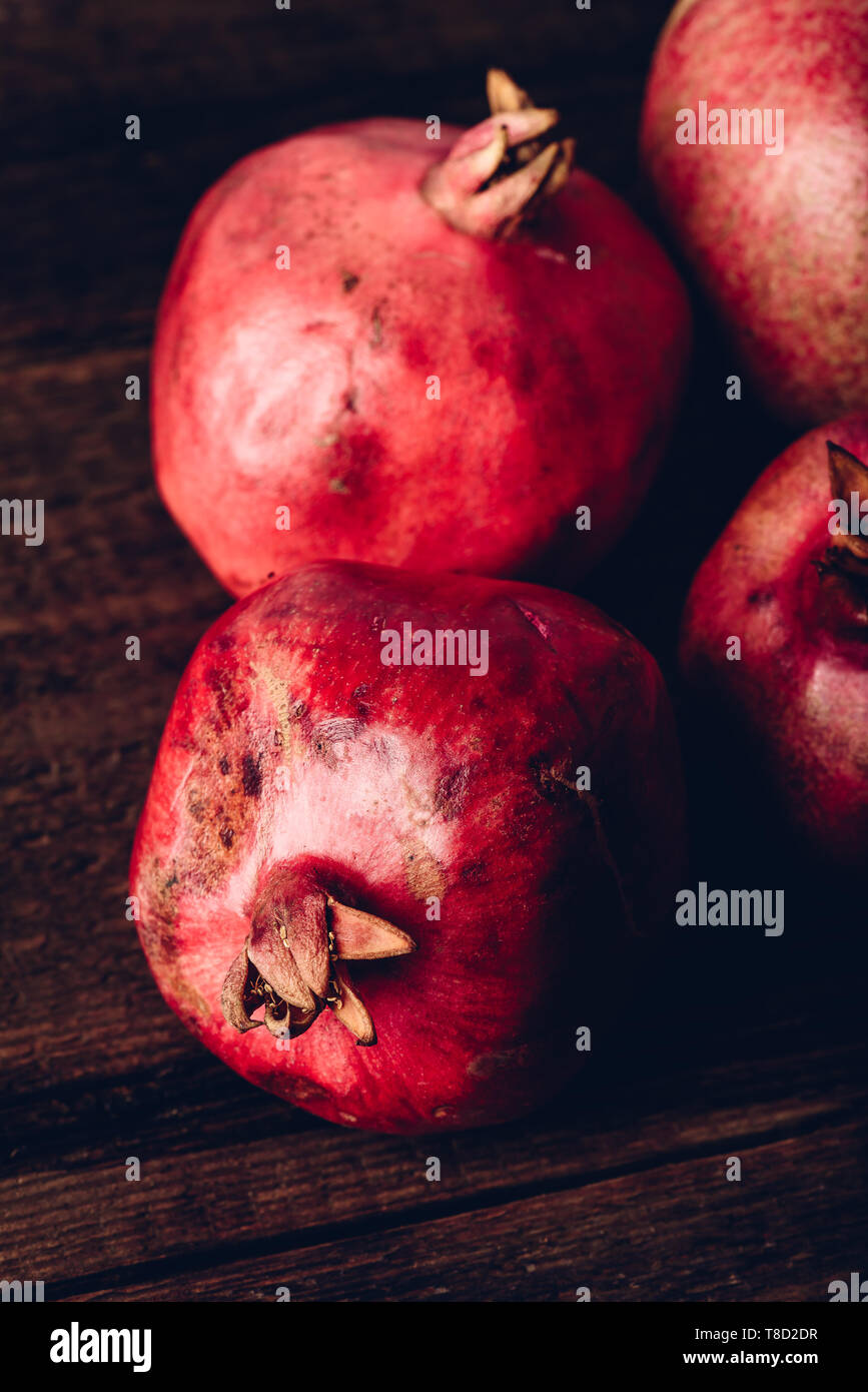 Four ripe pomegranate on rustic wooden table Stock Photo