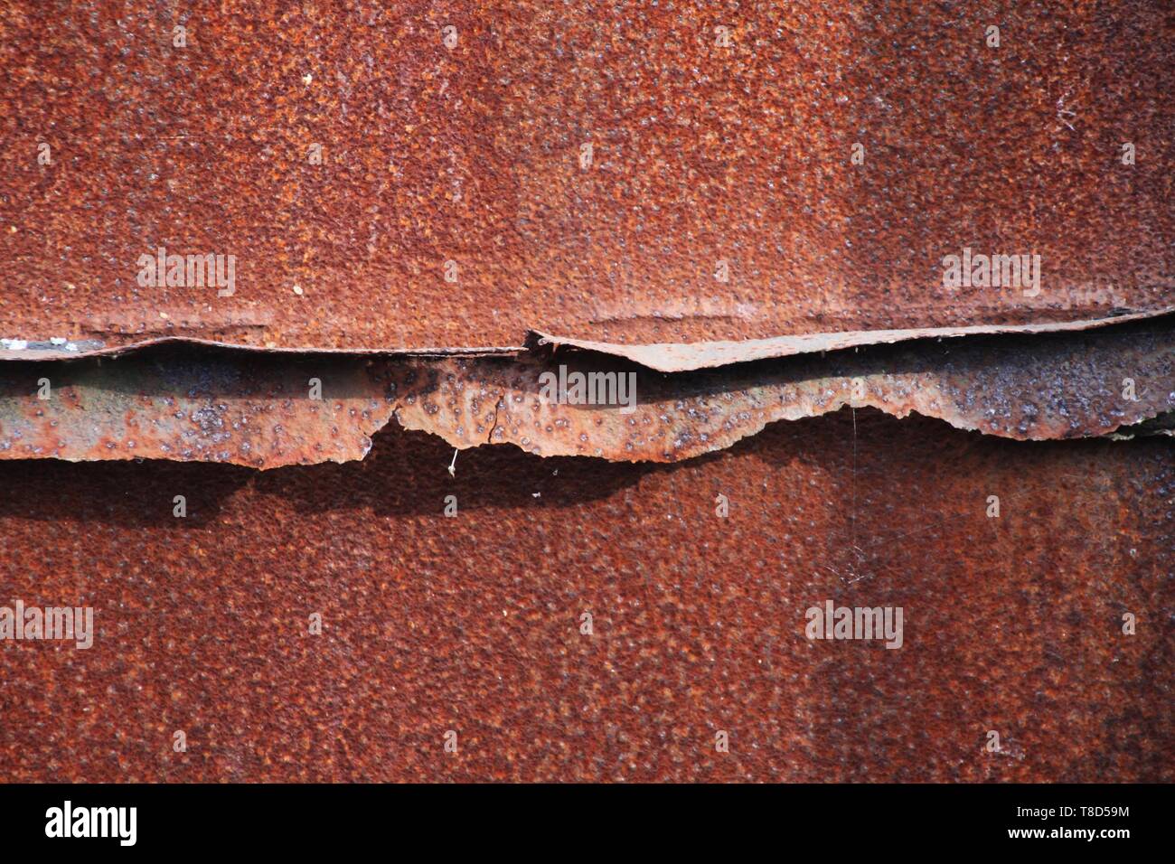 Landschaftspark Duisburg, Germany: Close up of rusty sprinkled corroded weathered brown metal rough surface with cracked welding seam Stock Photo