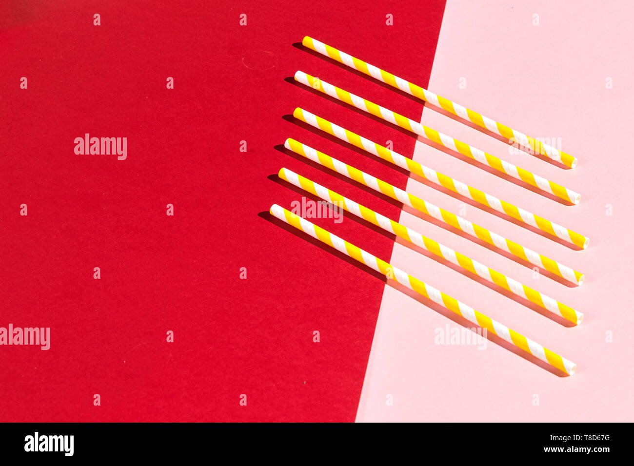 different drinking straws over pink and red background, top view. copy