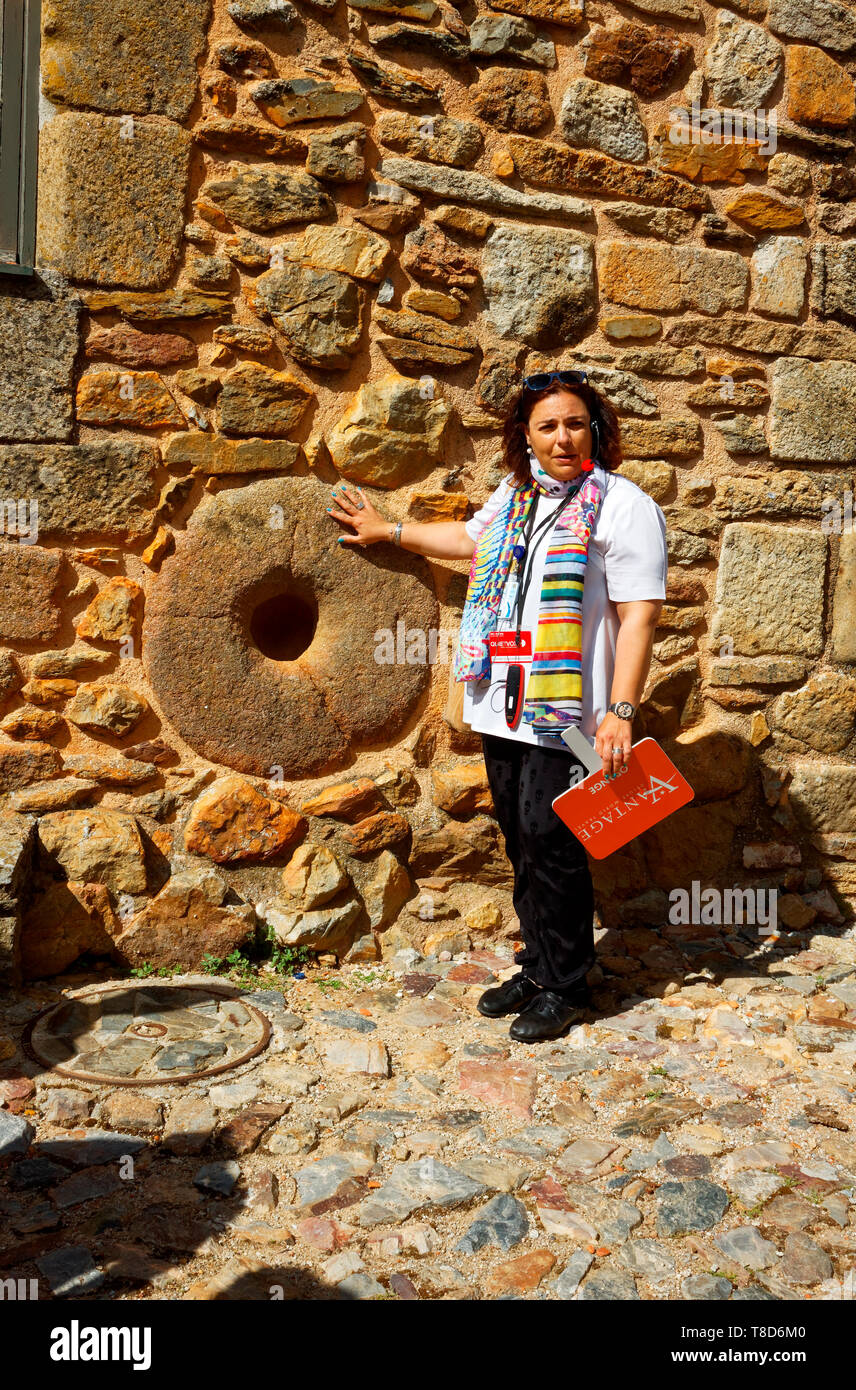 female guide, job, explaining round wall opening to ferment cheese, historic village; medieval; old stone building; Europe; Castelo Rodrigo; Portugal; Stock Photo