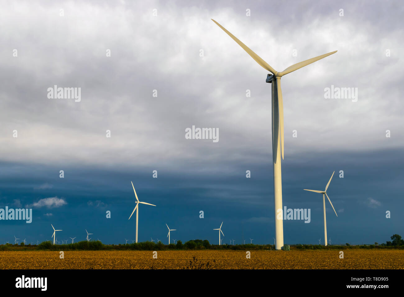 Wind Turbine during a cloudy day on a farm. Stock Photo