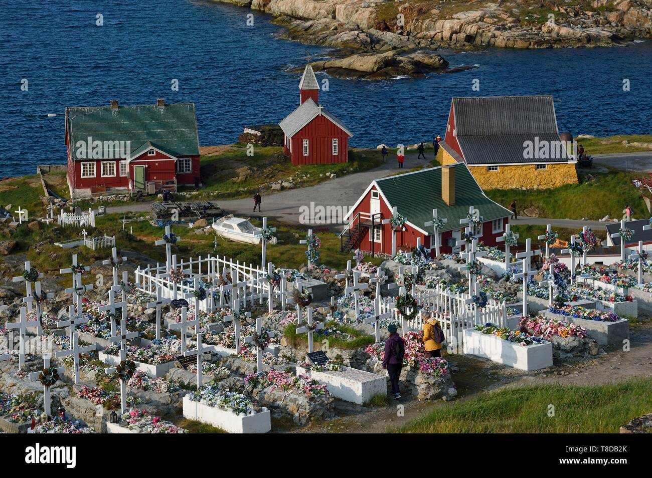 Greenland, west coast, Baffin Bay, Upernavik, the cemetery, the coffins are placed on the surface and then covered with stones or cement, the ground can not be dug, the tombs are then decorated with artificial flowers, the old church and the museum buildings in the background Stock Photo