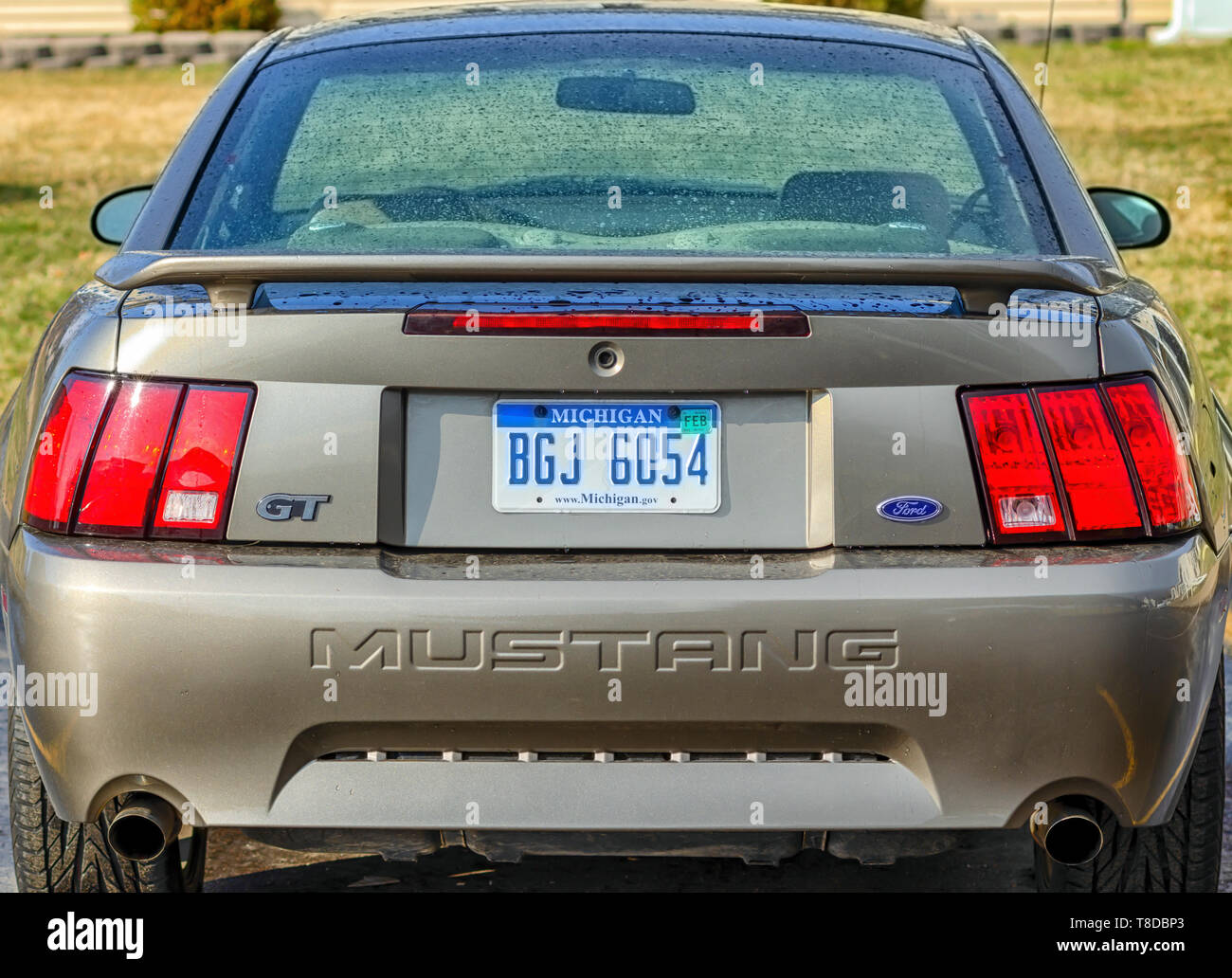 A rear profile/rear bumper of a 2001 Ford Mustang GT Coupe. Tiny drops of water cover the body of the sports car after a summer storm. Stock Photo