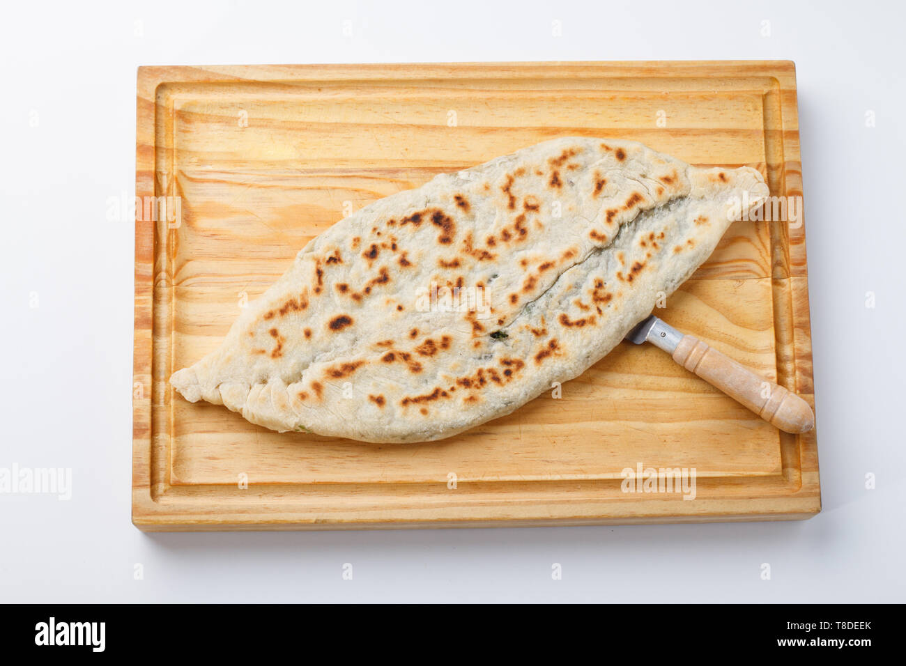 Freshly made Jingalov / Zhingyalov Hats; a traditional Armenian dish served on a wooden board, on a white background. Stock Photo