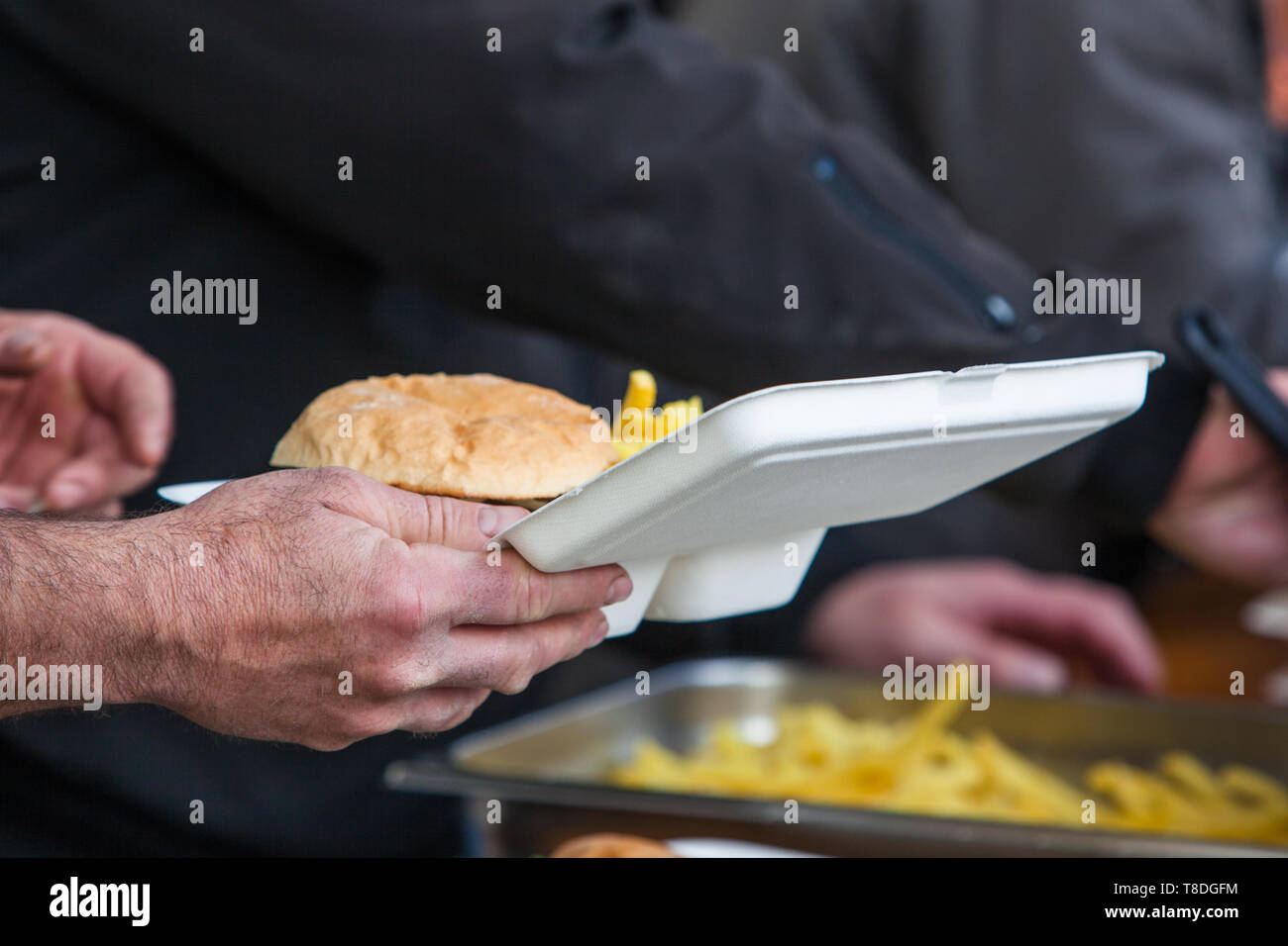 Ready take away meal plate with freshly cooked burger and french fries on outdoors kitchen at street music festival in Gland, Vaud, Switzerland Stock Photo