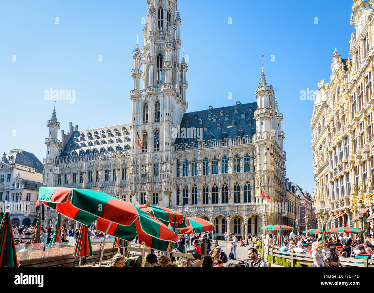 Tourists having a drink on the terrace of a cafe on the Grand Place in Brussels, Belgium, opposite the town hall and its 96-metre-high belfry. Stock Photo