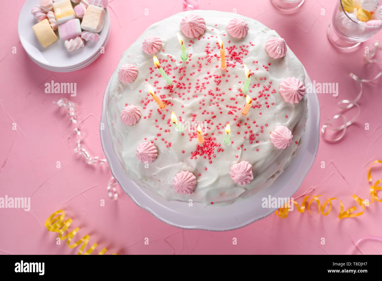 Tasty birthday cake with burning candles on color table Stock Photo - Alamy