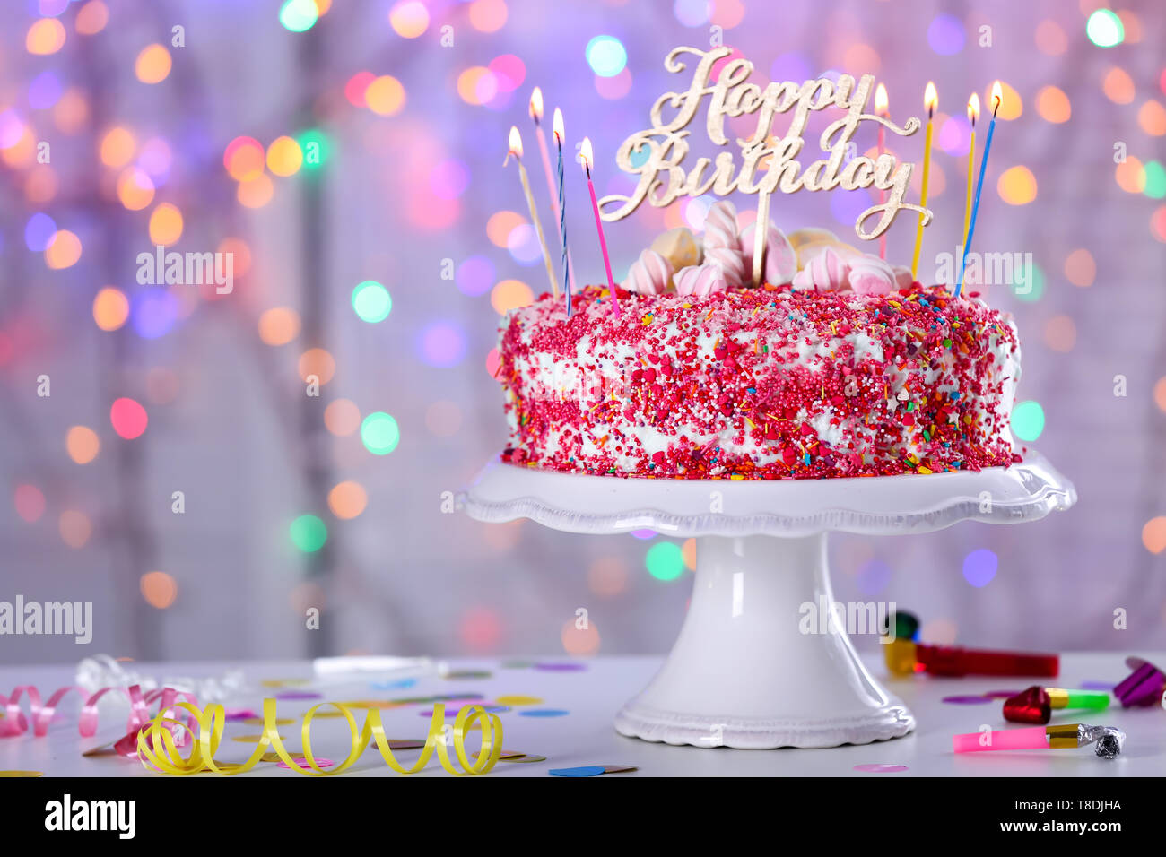 Tasty birthday cake with burning candles on table against defocused ...