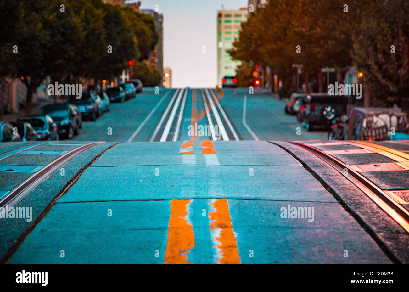 Low angle twilight view of an empty road with cable car tracks leading up a steep hill at famous California Street at dawn, San Francisco, California, Stock Photo