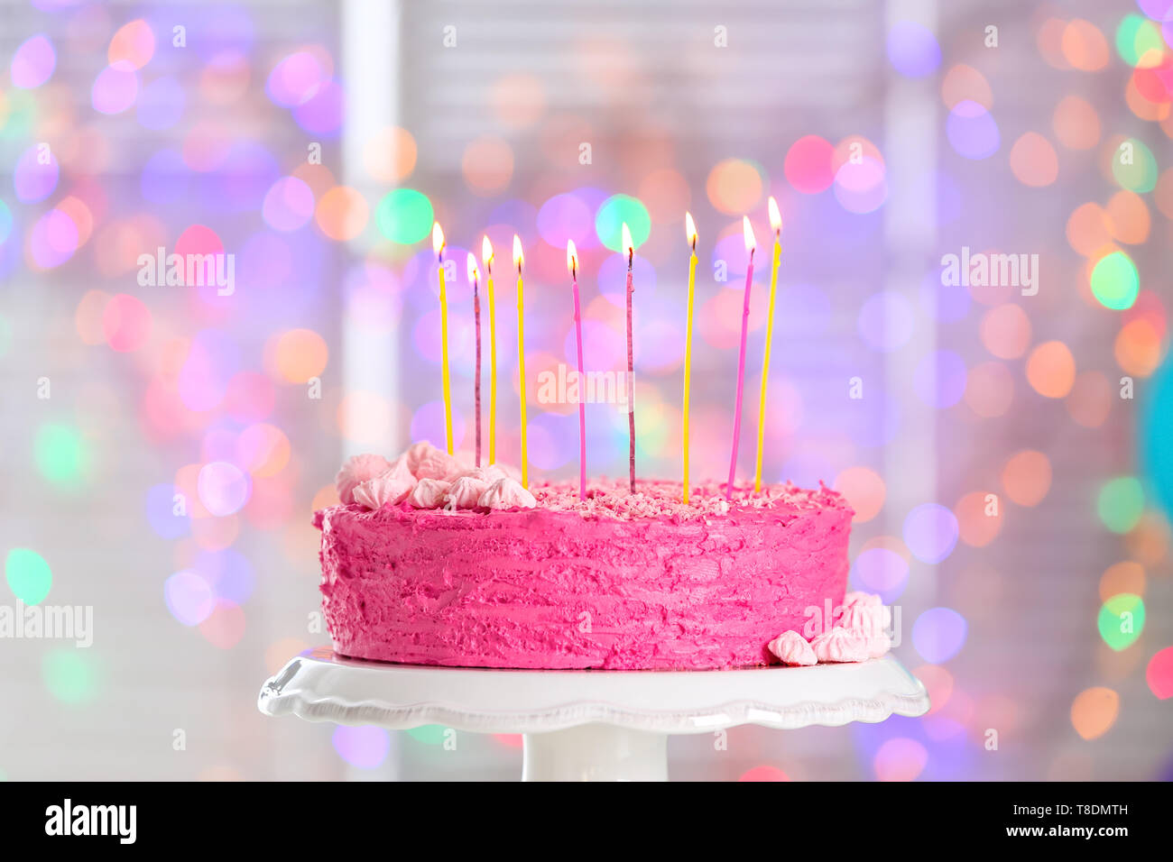 Stand with delicious birthday cake and burning candles against blurred ...