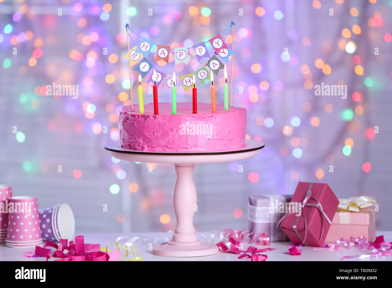 Stand with delicious birthday cake and burning candles on table against ...