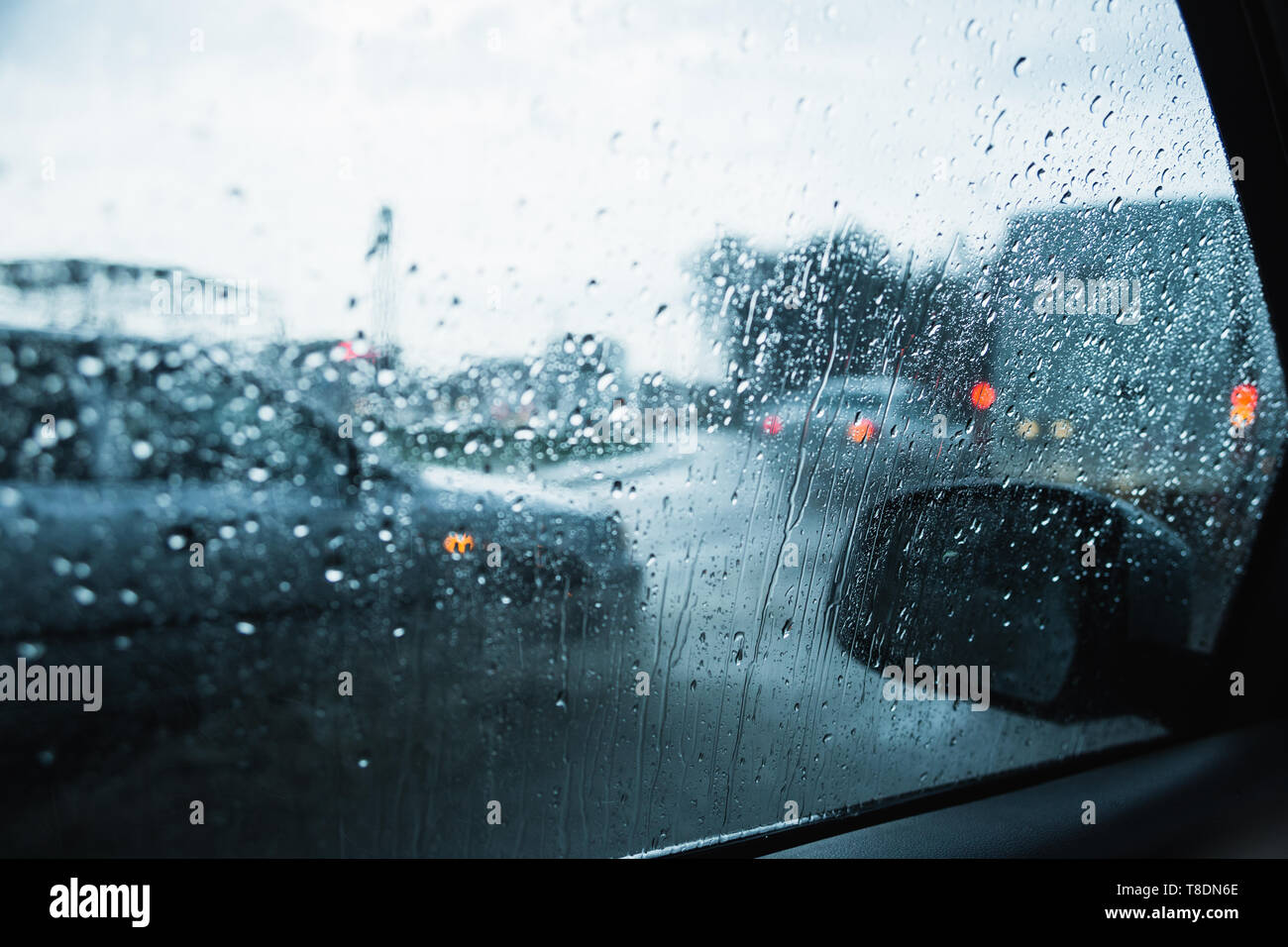 City road through windshield cars abstract background water drop on the glass lights and rain. Stock Photo
