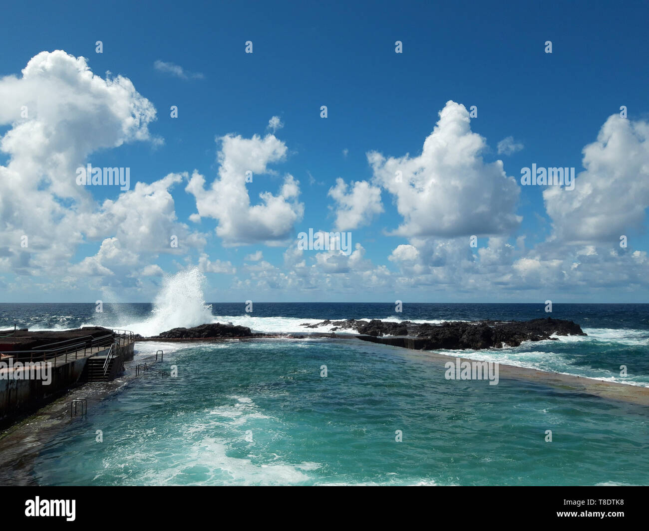 ocean wave splash on rocks at coast on a sunny day with blue sky Stock Photo