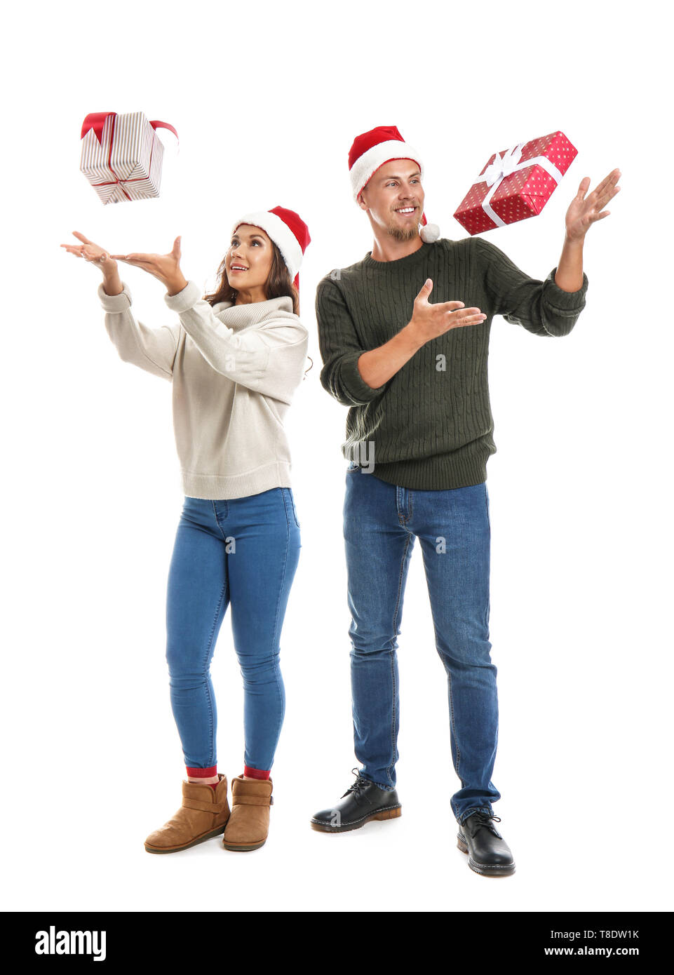 Portrait of cute young couple catching Christmas presents on white ...