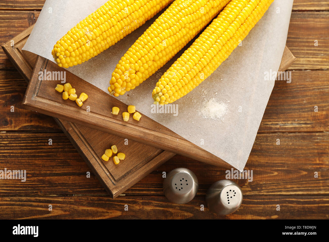 Board with tasty corn cobs on wooden table Stock Photo