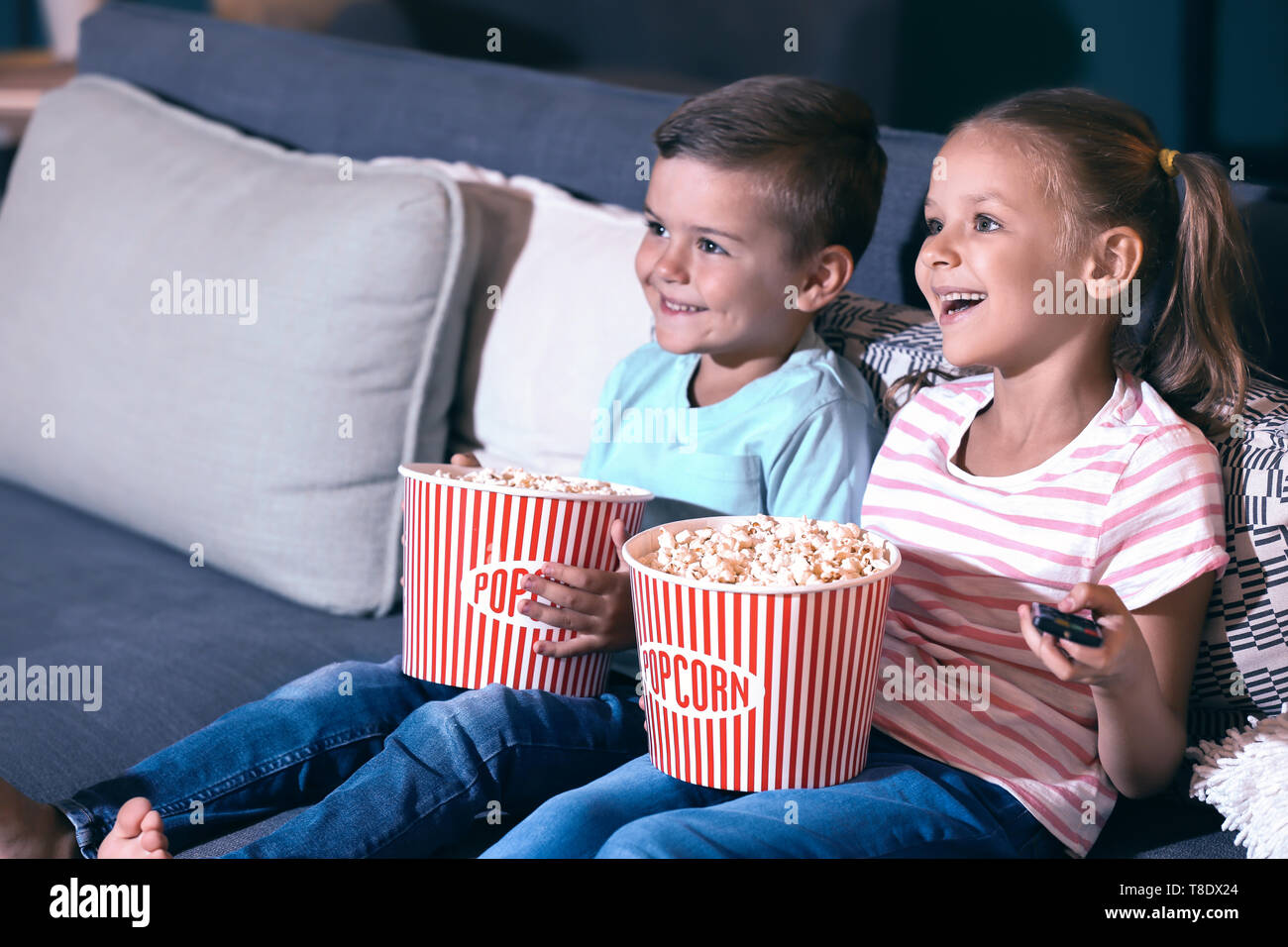 Children eating popcorn while watching TV in evening Stock Photo Alamy