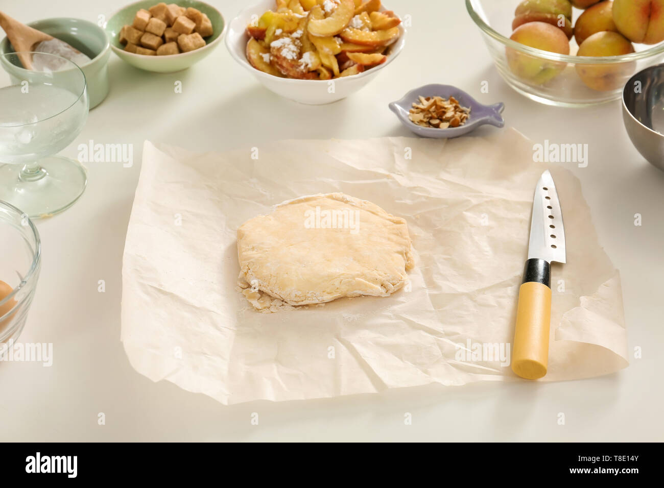 Raw dough and ingredients for preparing peach galette on light table Stock Photo