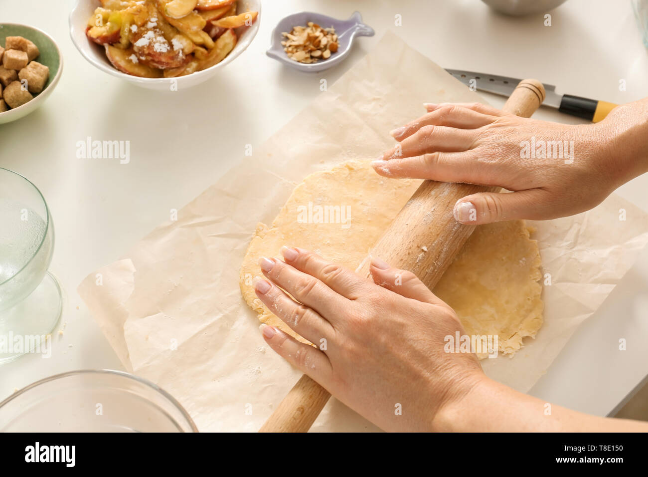 Woman rolling dough at light table, closeup Stock Photo