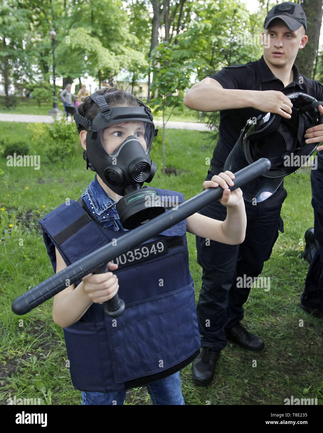 Kiev, Ukraine. 12th May, 2019. A little girl poses for a photo wearing riot police equipment during 'City of professions' children's festival in Kiev, Ukraine, on 12 May 2019. The City of Professions is a children's career-oriented festival whose goal is to provide children to try themselves in different professions - rescuers, firemen, bomb experts, policemen, doctors, social workers, criminologists, aircraft designer, atomic engineer, a businessman, a scientist, and others. Credit: Serg Glovny/ZUMA Wire/Alamy Live News Stock Photo