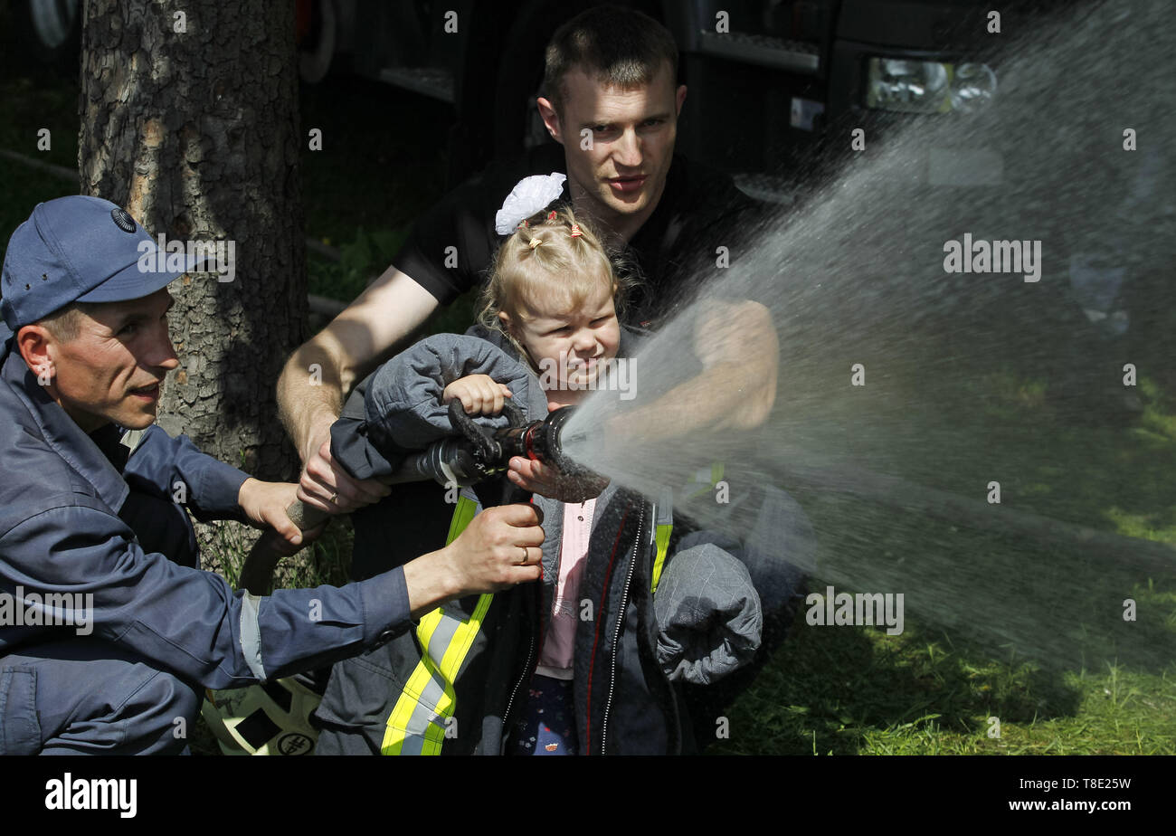 Kiev, Ukraine. 12th May, 2019. A little girl pours water from fire hose during 'City of professions' children's festival in Kiev, Ukraine, on 12 May 2019. The City of Professions is a children's career-oriented festival whose goal is to provide children to try themselves in different professions - rescuers, firemen, bomb experts, policemen, doctors, social workers, criminologists, aircraft designer, atomic engineer, a businessman, a scientist, and others. Credit: Serg Glovny/ZUMA Wire/Alamy Live News Stock Photo