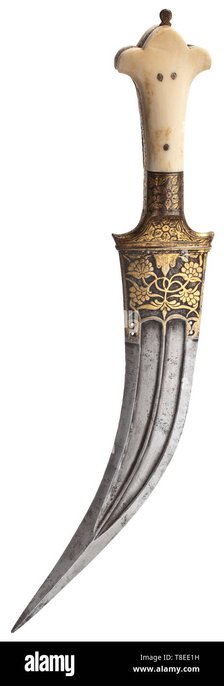 An Indian tiger tooth dagger, circa 1800 Curved, double-edged blade of Wootz Damascus with reinforced quadrangular point and double fullers on both sides. The base of the blade with chiselled and gilt décor of lotus leaves. Finely engraved iron grip ferrule and grip strap with gilt scrolling flowers and leaves. Riveted ivory grips. Length 31 cm. historic, historical, 19th century, Additional-Rights-Clearance-Info-Not-Available Stock Photo