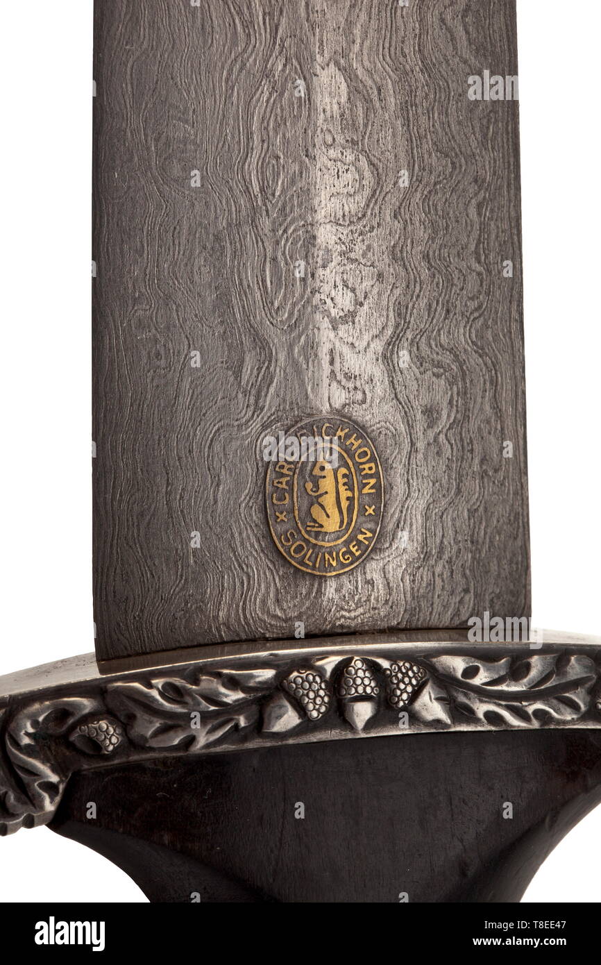 An SS honour dagger with Damascus blade Damascus blade with highly etched, gilt device 'Meine Ehre Heißt Treue' (tr. 'My honour is loyalty') between oak leaf branches, the reverse with the highly etched and gilt maker's logo of Eickhorn, Solingen. Silver grip fittings with a relief-worked oak leaf décor, black wooden grip (small crack) with nickel-silver national eagle and enamelled emblem. The steel scabbard with the original black leather covering (minimal flaws), silver-plated scabbard fittings. With a short, two-piece leather hanger with RZM stamping. Length 37 cm. An e, Editorial-Use-Only Stock Photo